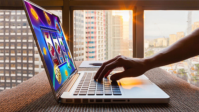 Hand Reaching Out to Laptop Displaying Online Slot Game